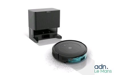 a close up of a robot vacuum and a box on a white surface