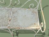 a white bench with a metal frame on a green background