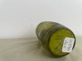 a green bottle with a tag on it sitting on a table