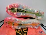 two pairs of soccer cleats sitting on top of a pink bag