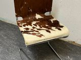 a brown and white cow print chair with a metal frame