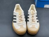 pair of white and black sneakers on a black surface with a box of blue boxes in the background
