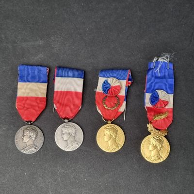 four medals are shown on a black surface with a red, white, and blue ribbon