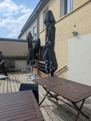 tables and chairs on a wooden deck with umbrellas on a sunny day