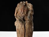 sculpture of a man sitting on a tree stump with a bird on his shoulder