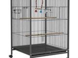 une grande cage à oiseaux noire, équipée d'un perchoir en bois et de roulettes
