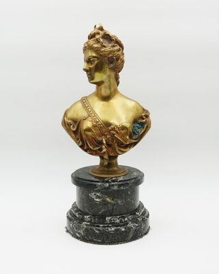 a gold busturine of a woman on a marble base