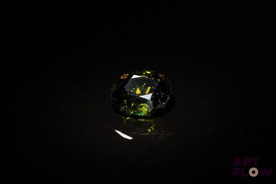 un gros plan d'un diamant vert et noir sur une surface noire