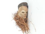 a wooden mask hanging on a wall with a nest in it
