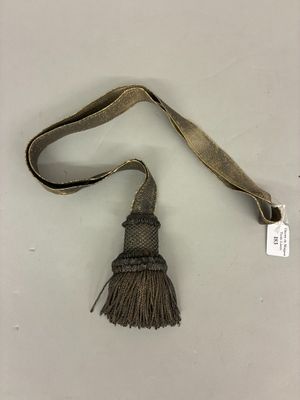 an old tassel with a tag attached to it on a white surface