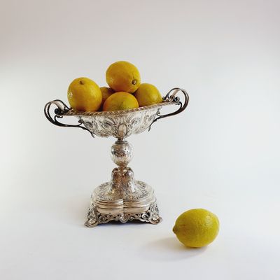 a silver bowl filled with lemons next to a lemon