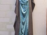a blue dress hanging on a clothes rack in the corner of a room
