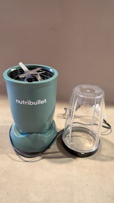 un petit mixeur posé sur un plan de travail, à côté d'une tasse