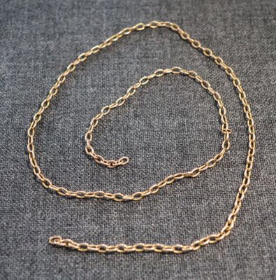 une chaîne plaquée or avec un fermoir, posée sur un tissu gris