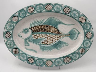 a plate with a fish design on it on a stand