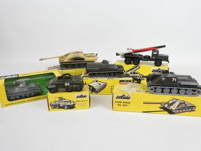 Plusieurs véhicules militaires miniatures sont alignés sur une surface blanche