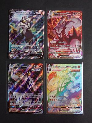 quatre cartes Pokémon différentes posées sur une table noire