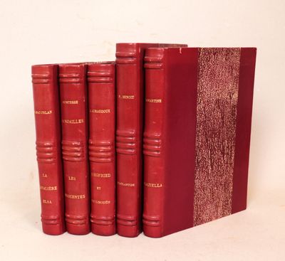 trois livres rouges sont empilés sur une surface blanche
