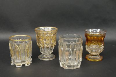 several different colored glass cups and glasses on a black surface