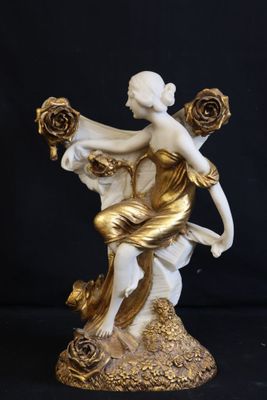 statue of a woman sitting on a rock holding a bouquet of roses