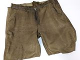 un gros plan sur un pantalon marron posé sur une surface blanche