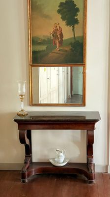 un tableau accroché au mur au-dessus d'une table sur laquelle se trouvent une tasse et une soucoupe