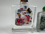 a glass bottle with a painting on it next to a glass bottle with a painting on it