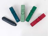 Quatre stylos en cuir de couleurs différentes sont alignés sur une surface blanche