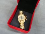 gold watch in a red box on a table with a black cloth