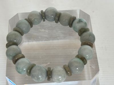 un bracelet composé de perles de jade vert, présenté dans une vitrine transparente