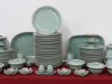 many plates and bowls on a table with a red table cloth
