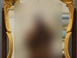 un miroir ancien dans un cadre doré, posé sur un socle en bois, avec un fond noir
