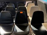 plusieurs chaises noires et blanches dans une pièce où se trouve une horloge accrochée au mur