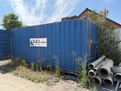 a blue container with a sign on it next to a pile of pipes