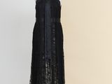 une robe noire posée sur un mannequin, devant un mur beige