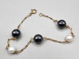 a black and white bracelet with pearls on a gold chain