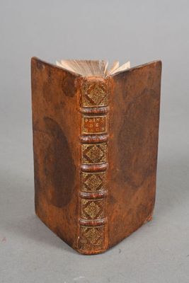 an old book is sitting on a table with a gray background