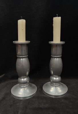 pair of silver candle holders with candles on a black background
