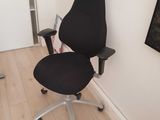 a black office chair with a black seat in the corner of a room