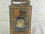 a small brass clock with a wooden handle on a white table