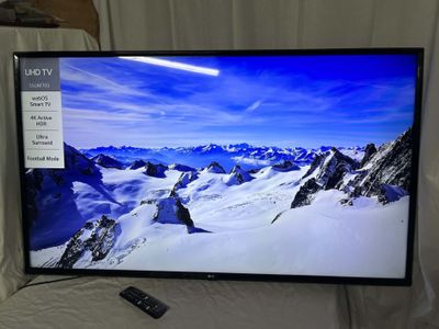 La télévision à écran plat est posée sur un lit, avec une télécommande à côté.
