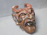 a ceramic mask with horns on it on a white surface