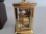 a small gold clock sitting on a table next to a box