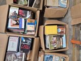 Plusieurs cartons remplis de livres sont posés par terre à côté d'une paire de ciseaux