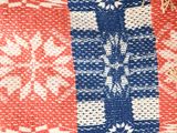 a red, white and blue knitted blanket on the floor