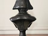 the bust of a man in a hat is sitting on a wooden floor
