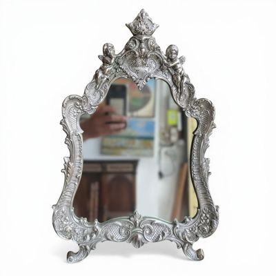 MIROIR à poser de style rocaille surmonté de deux putti, en …