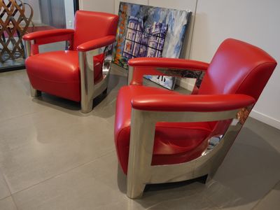 two red chairs in a room with a painting on the wall