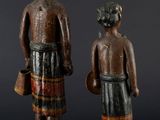 two wooden statues of a man and a woman standing next to each other