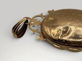 a gold pocket watch with a chain on a white surface